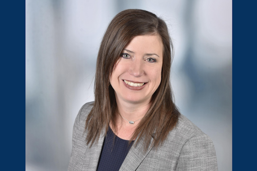 headshot of woman in gray blazer and navy blue shirt